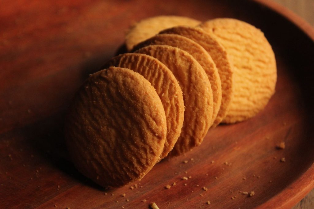 Delicious golden brown biscuits arranged neatly on a rustic wooden plate.